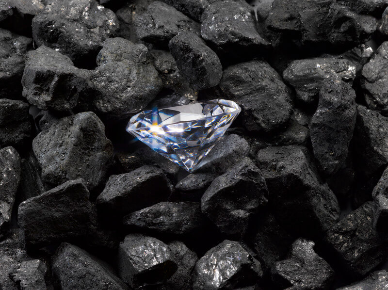 A diamond laying in the middle of a pile of coal