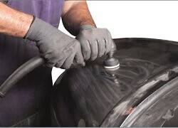 a man wearing gloves using a steel polishing machine